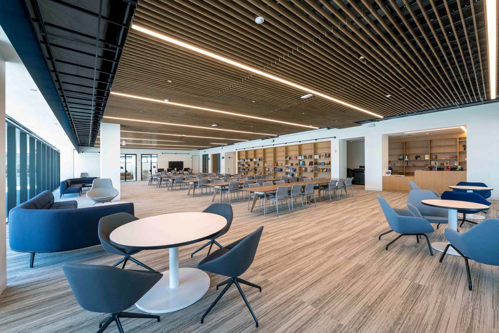 NYC Korean Cultural Center Korean-Cultural-Center-Rendering-5 Large dining and study area with modern furniture and wooden ceiling accents.